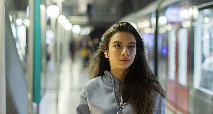 Vrouw met oordopjes op het treinstation