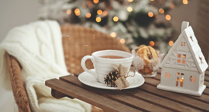 Tafel met warme thee en kaarshuisje in winterse sferen