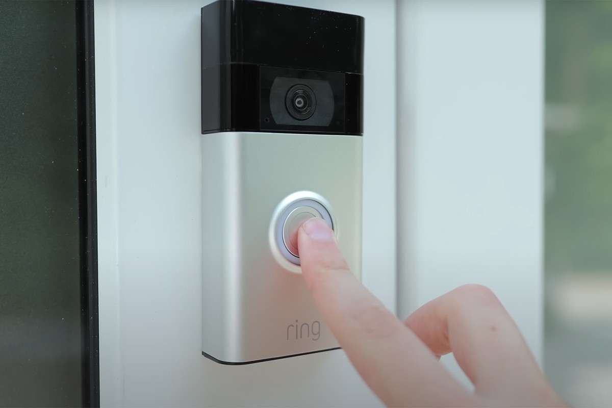 Ring videodeurbel Ring videodeurbel aan de deurpost wordt ingedrukt met wijsvinger