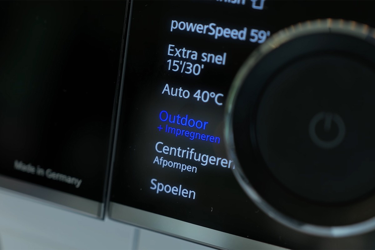 Een close-up van het bedieningspaneel van een wasmachine, waarop het programma “Outdoor + Impregneren” geselecteerd is