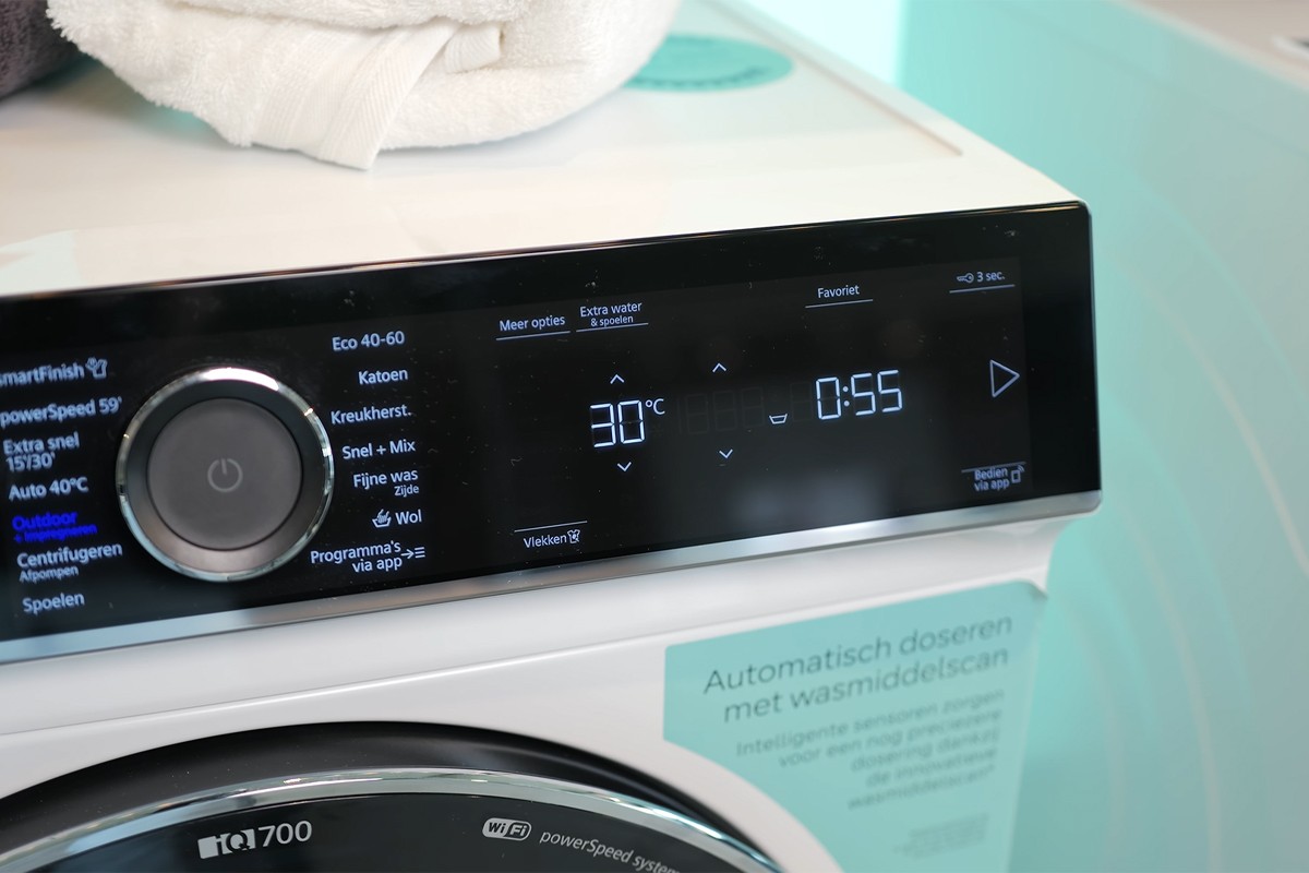 Een close-up van het bedieningspaneel van een Siemens iQ700 wasmachine met draaiknop en display, waarbij het programma “Outdoor + Impregneren” is geselecteerd en het display aangeeft dat er gewassen wordt op 30°C gedurende 55 minuten