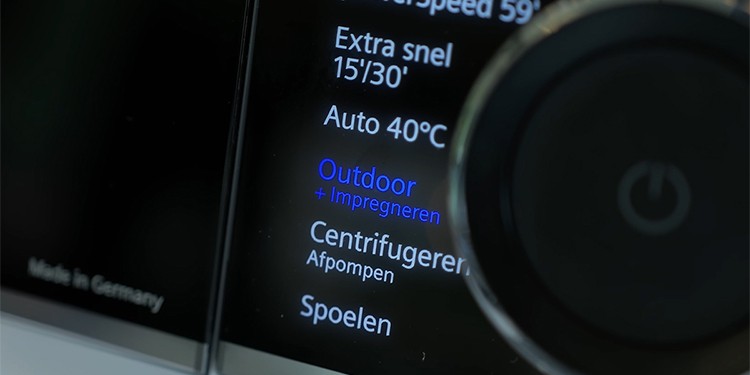 Een close-up van het bedieningspaneel van een wasmachine, waarop het programma “Outdoor + Impregneren” geselecteerd is