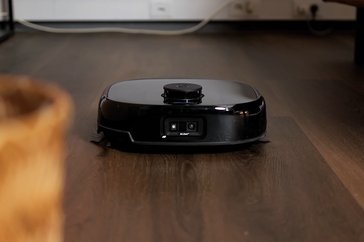 Eufy Omni E28 robotstofzuiger De Eufy Omni E28 rijdt over een donker houten vloer. Aan de voorzijde is een dubbele camera zichtbaar.