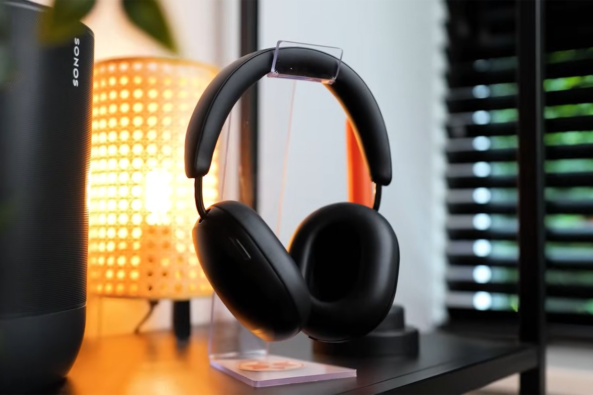 Een zwarte over-ear koptelefoon hangt op een transparante standaard op een zwarte plank.