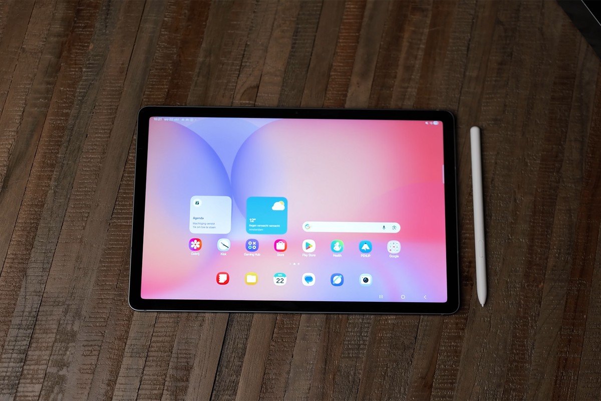 Een bovenaanzicht van een Samsung Galaxy Tab S10 Lite met bijbehorende stylus, liggend op een houten tafel.