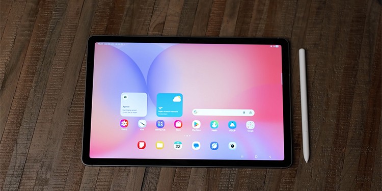 Een bovenaanzicht van een Samsung Galaxy Tab S10 Lite met bijbehorende stylus, liggend op een houten tafel.