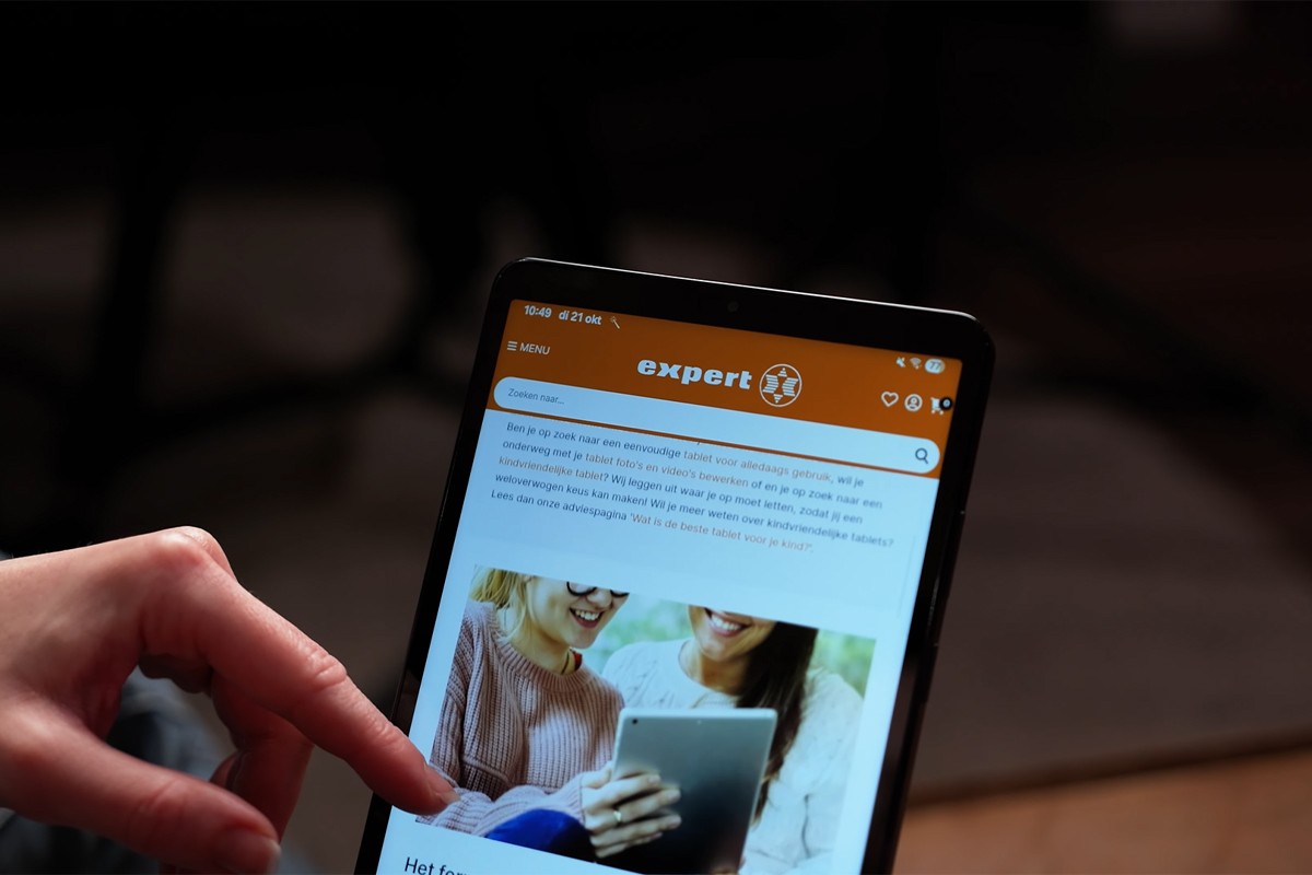 Een persoon scrolt met een vinger op het scherm van de Samsung Galaxy Tab A11 waarop de website van Expert wordt weergegeven.