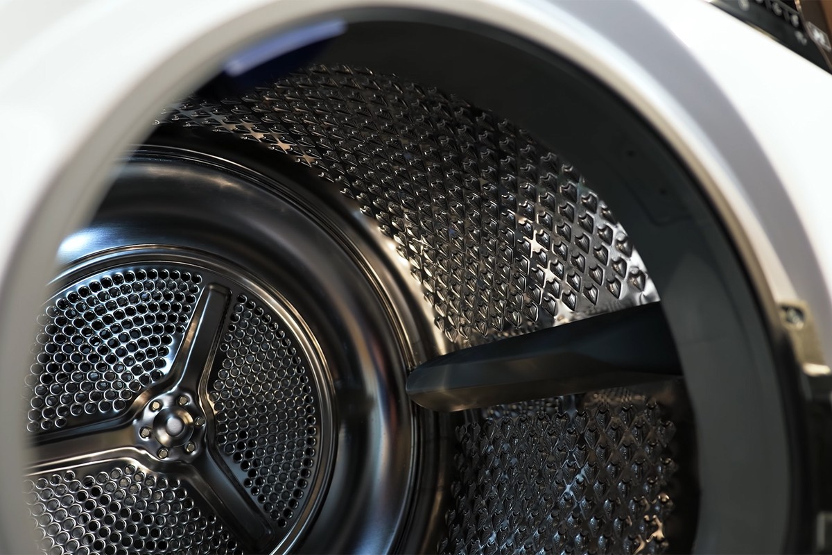 Close-up van de binnenkant van de Whirlpool-wasmachine laat de roestvrijstalen trommel zien met een glanzende structuur.