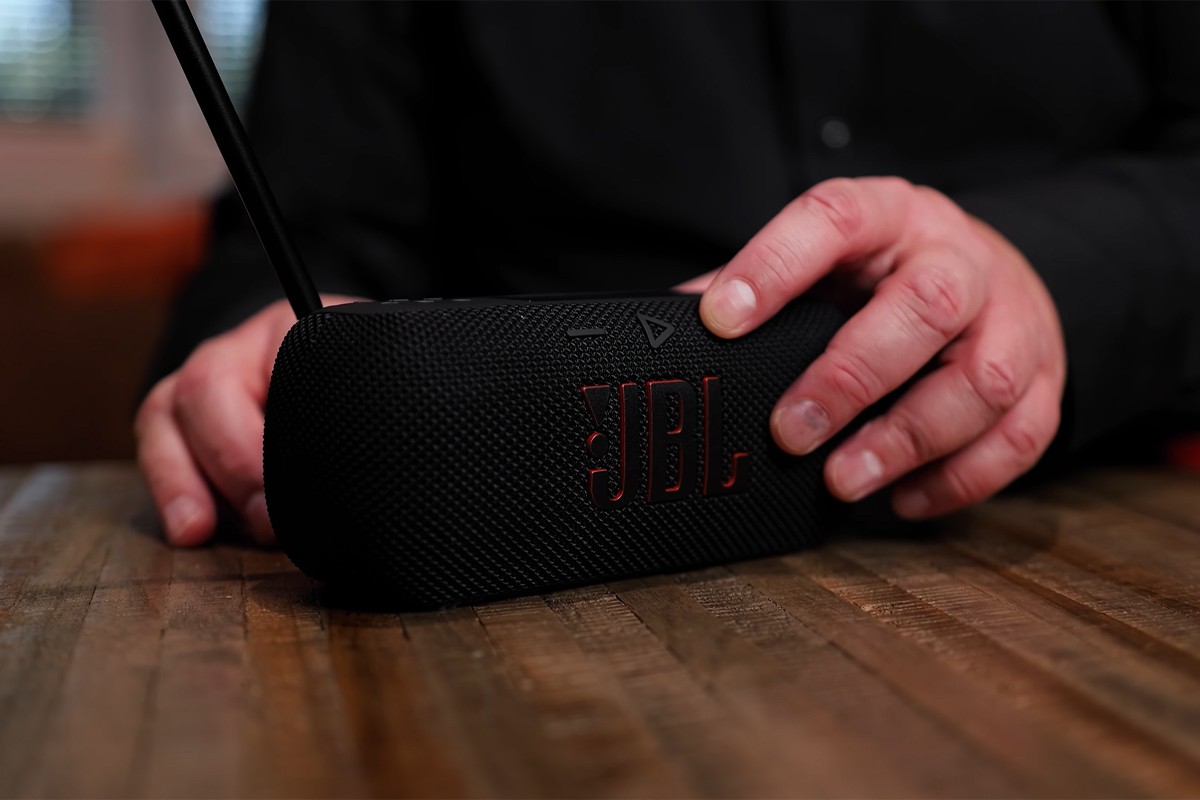 Persoon bedient de JBL Tuner 3 met de bedieningsknoppen bovenop het apparaat