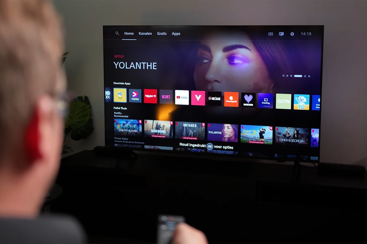 Persoon kijkt naar een tv waarop het smartplatform Titan OS goed te zien is.