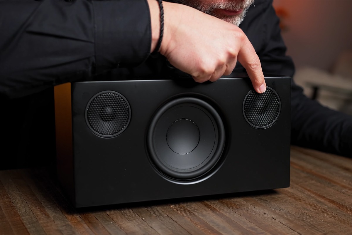 Close-up van de Audio Pro C10 MKII waar het magnetische front is afgehaald. Een persoon wijst één van de twee zichtbare tweeters aan.