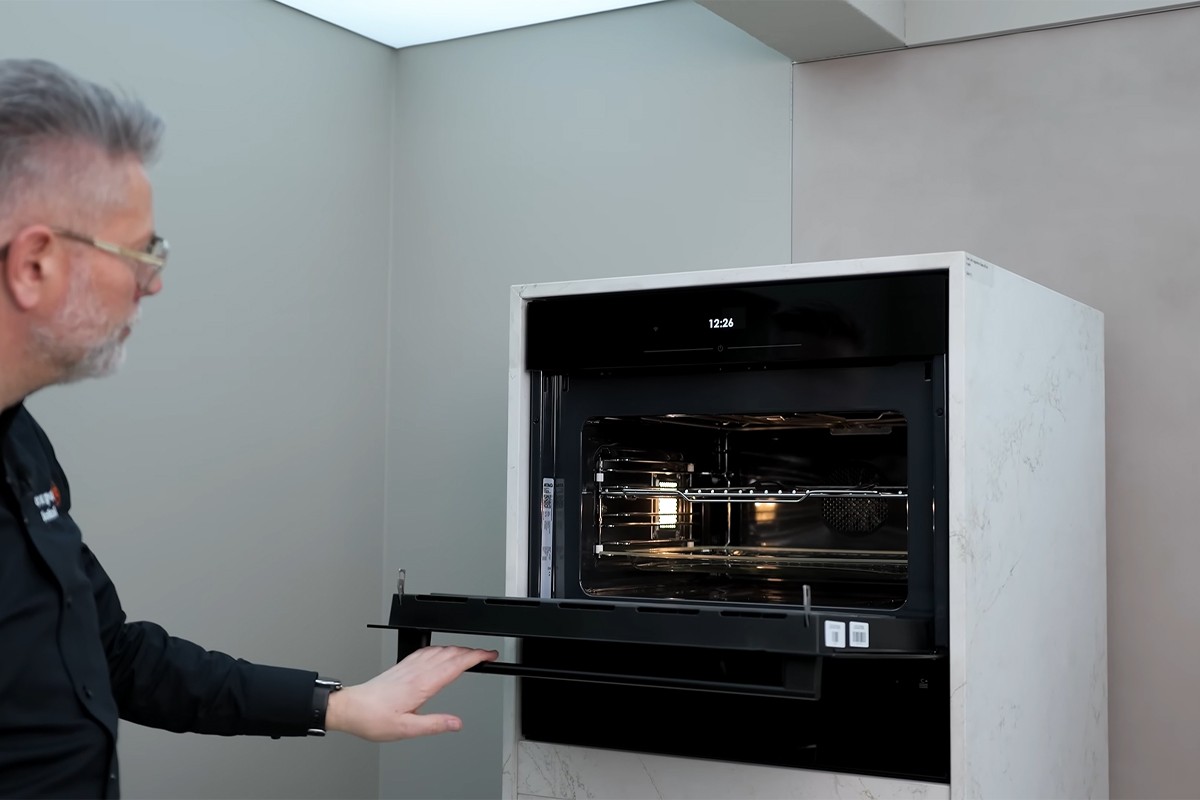 Persoon opent de Atag Serie 6 inbouwoven kijkt naar binnen.