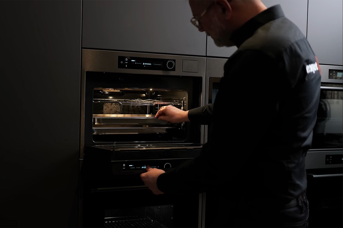 Persoon opent de ATAG Serie 8 inbouwoven en kijkt naar binnen.