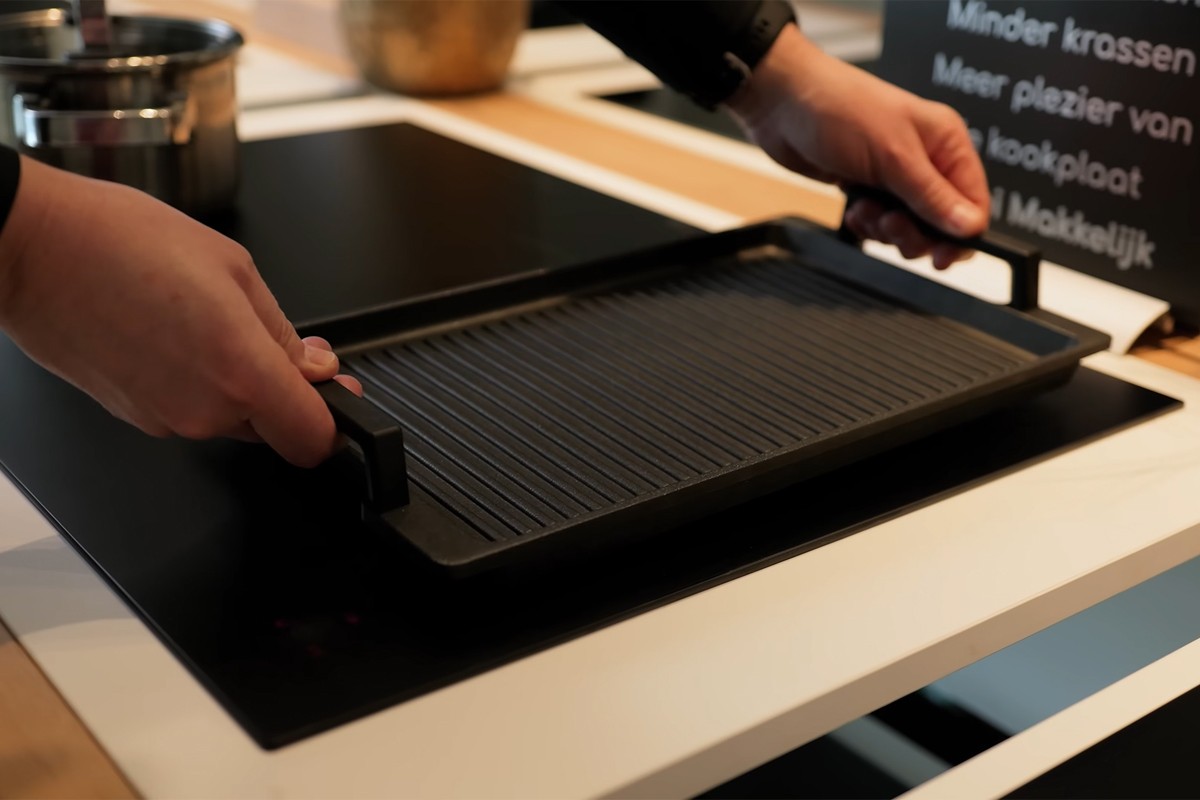 Persoon opent de ATAG Serie 8 inbouwoven en kijkt naar binnen.