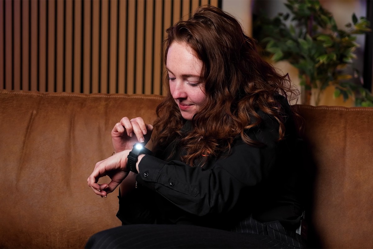 Persoon met Garmin Venu 4 om de pols probeert de ingebouwde zaklamp functie uit.