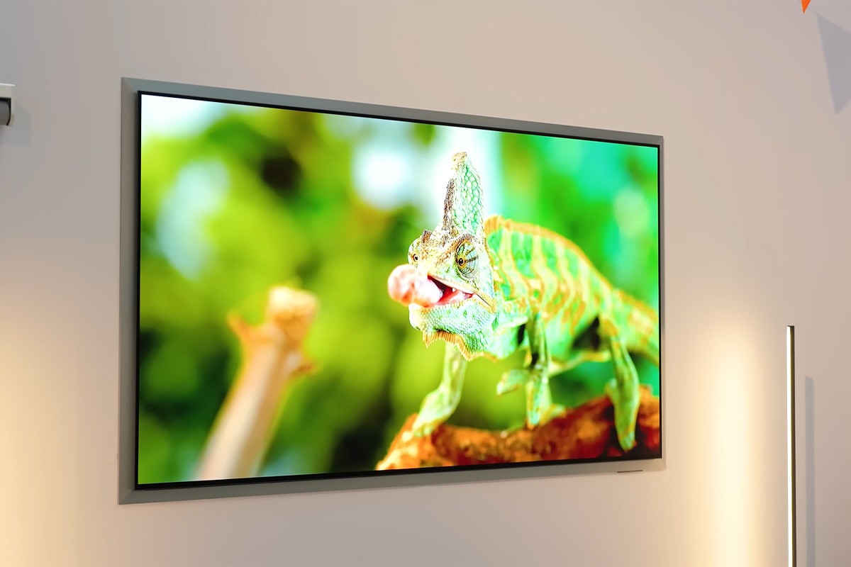 Hero shot van de Samsung S99H waarop een kameleon te zien is die met zijn tong een insect van een tak pakt.