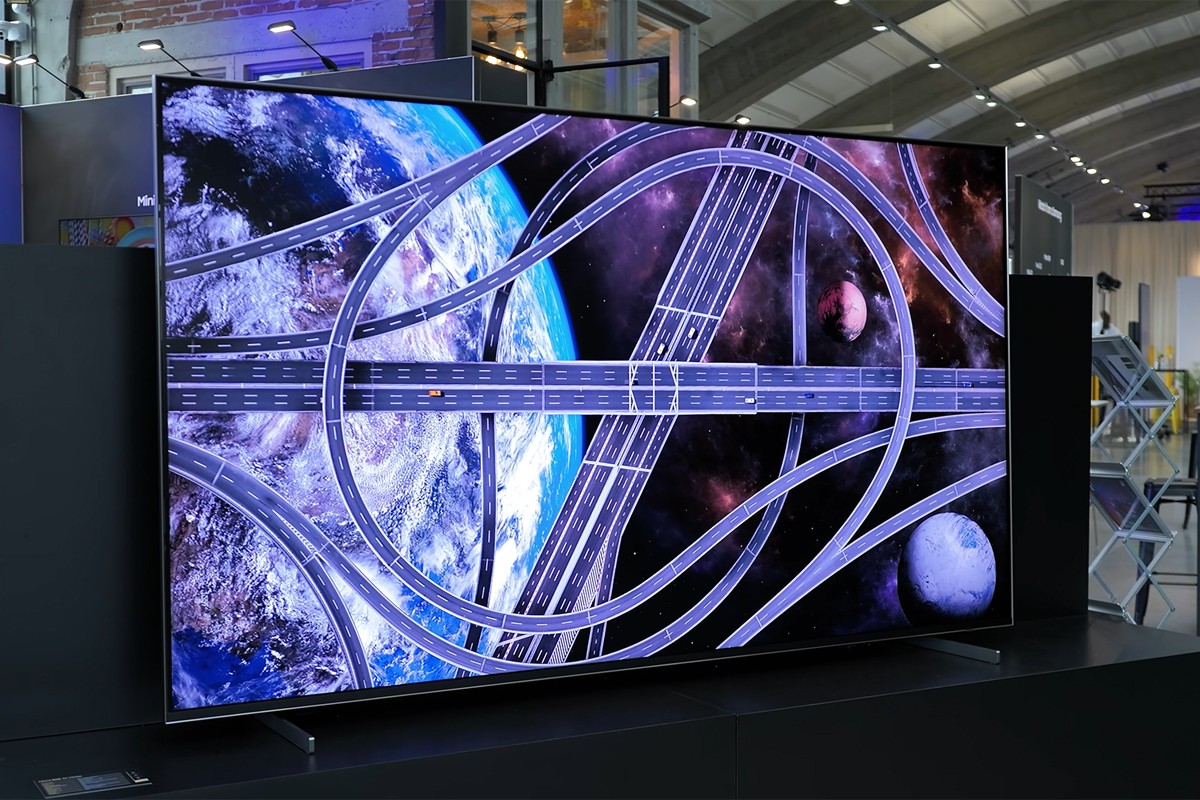 De Samsung R95H staat opgesteld in een grote showroom. Op het scherm is een beeld te zien van een knooppunt aan wegen dat samenkomt, gezien vanuit een helikopterview.
