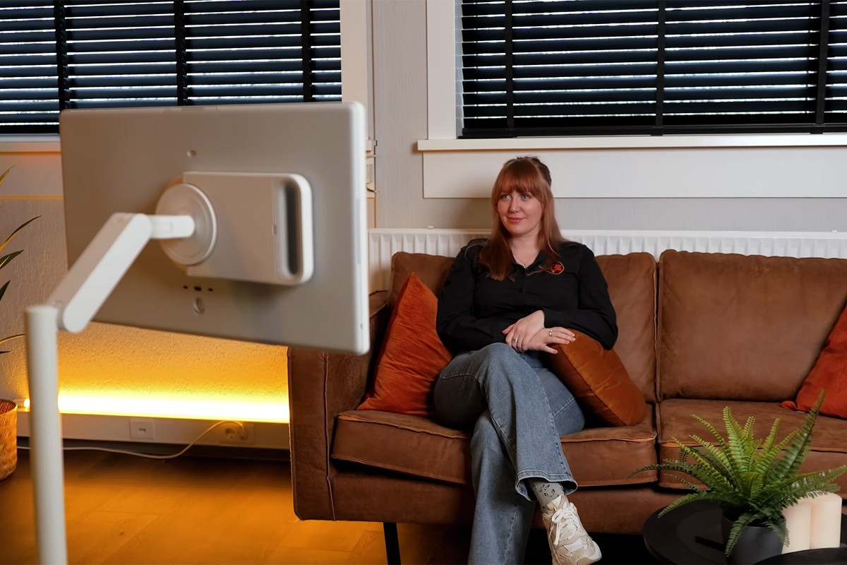 Persoon zit op de bank en kijkt naar de Samsung Movingstyle die op een standaard in de woonkamer staat.