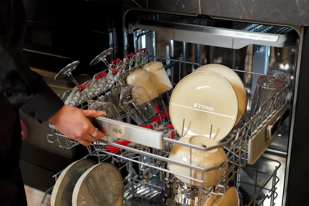 Close up van een persoon die de bovenste lade van de AEG Dish 8000-serie vaatwasser opentrekt.