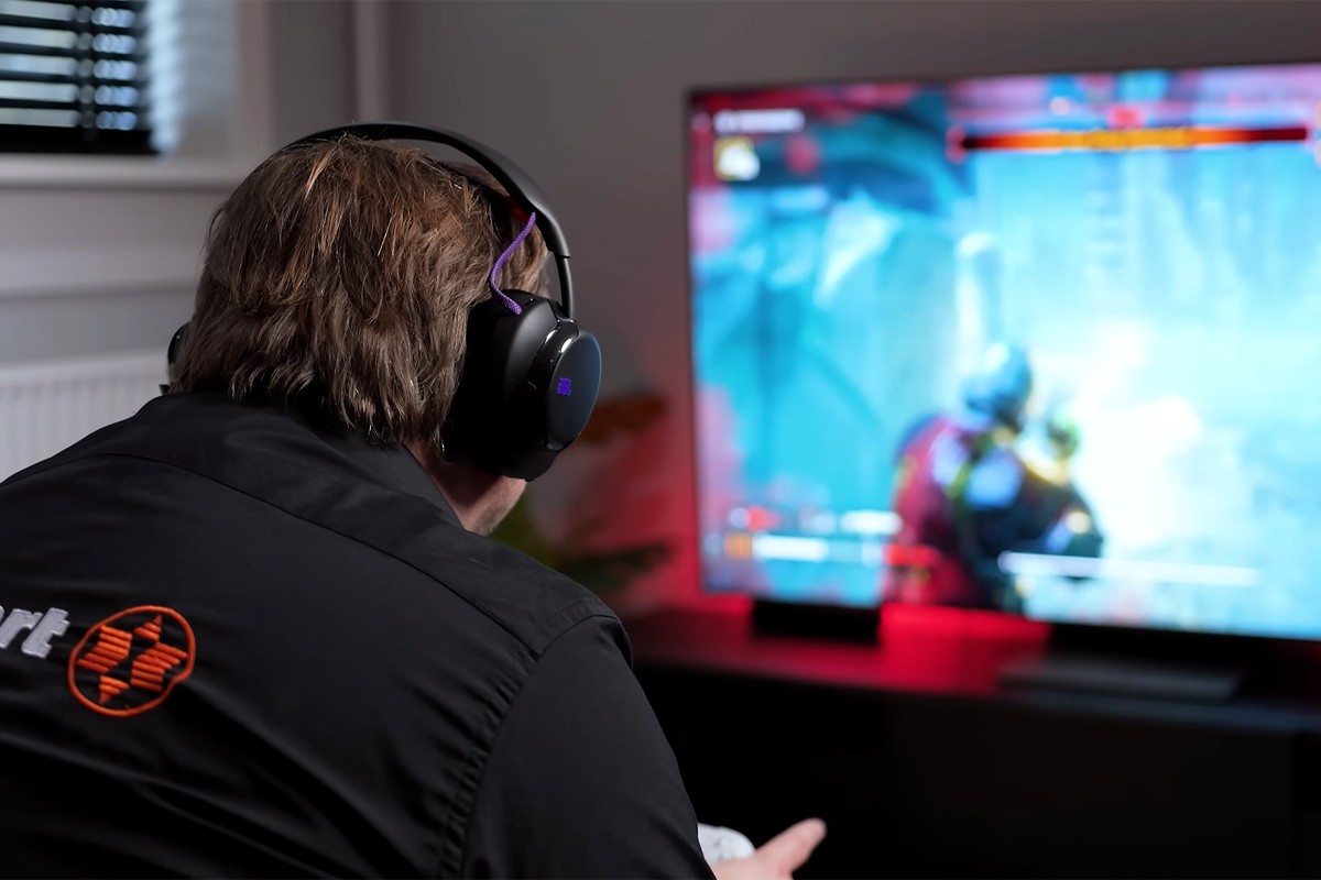 Persoon, gefotografeerd vanaf de achterkant, speelt een schietspel met de JBL Quantum 950 op z'n hoofd.
