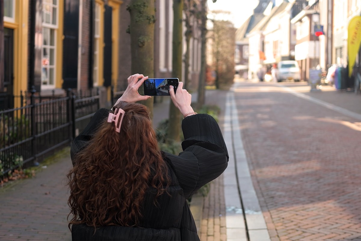 Persoon maakt foto met Samsung Galaxy S26 van een winkelstraat.