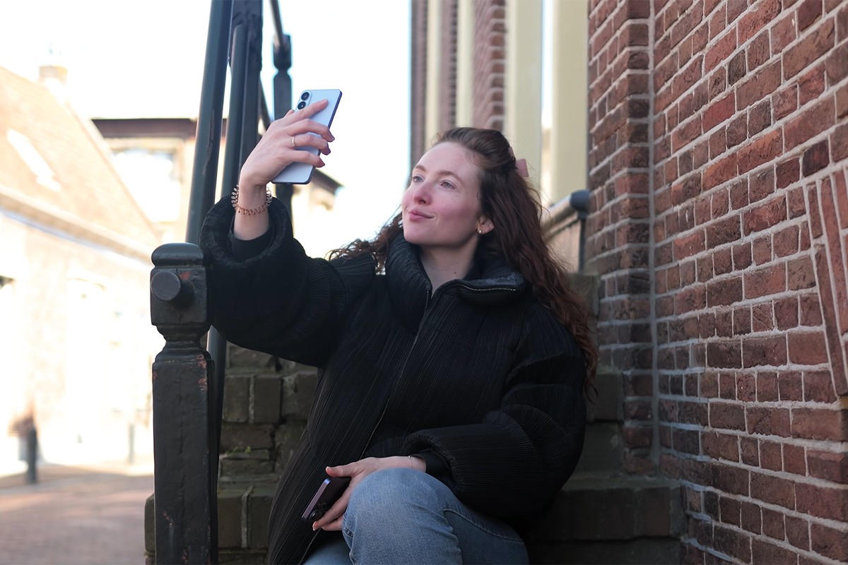Persoon zit op een stenen trap en neemt een selfie met de Samsung Galaxy S26.
