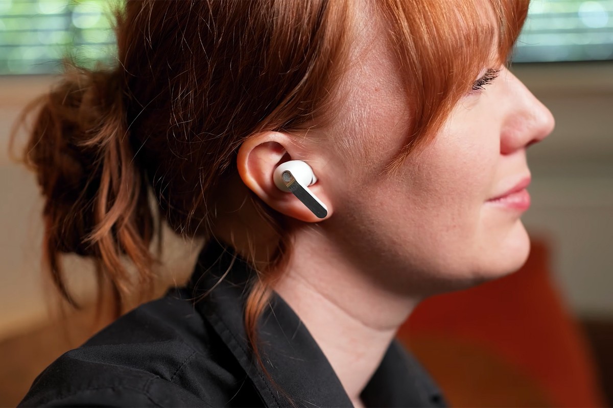 Close-up van een persoon die op de bank zit en de Samsung Galaxy Buds 4 in het oor draagt.