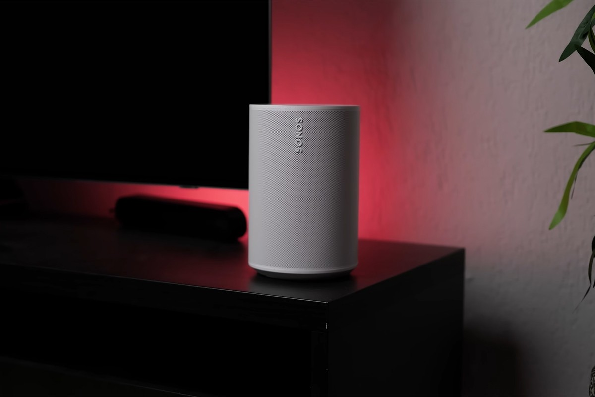 Sonos Era 100 SL op een tv-meubel met rode achtergrondverlichting.