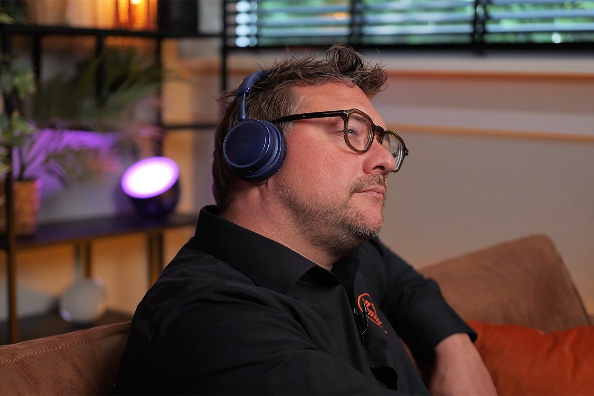 Persoon zit op de bank en luistert naar muziek op de JBL Live 680.